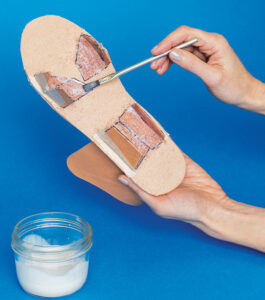 applying glue to tabs on bottom of sandal sole